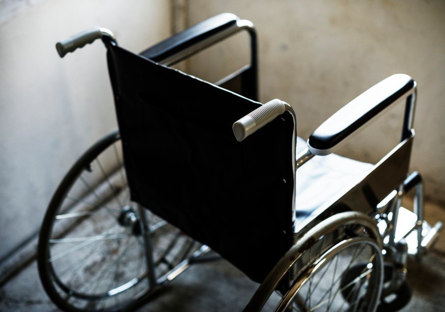 Black wheelchair with large rear wheels and metal armrests in an indoor room.