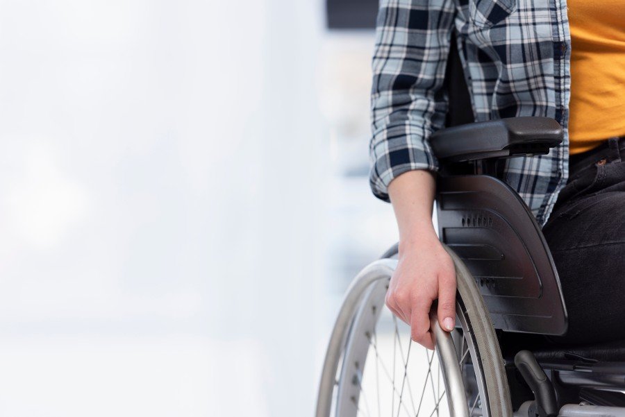 Person using a wheelchair, with a hand gripping the wheel, illustrating Wheelchair on Rent services.